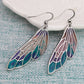 Pair of wing-shaped earrings with colorful design on a textured surface