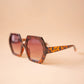 Sunglasses with leopard print frame and brown lenses on a beige background
