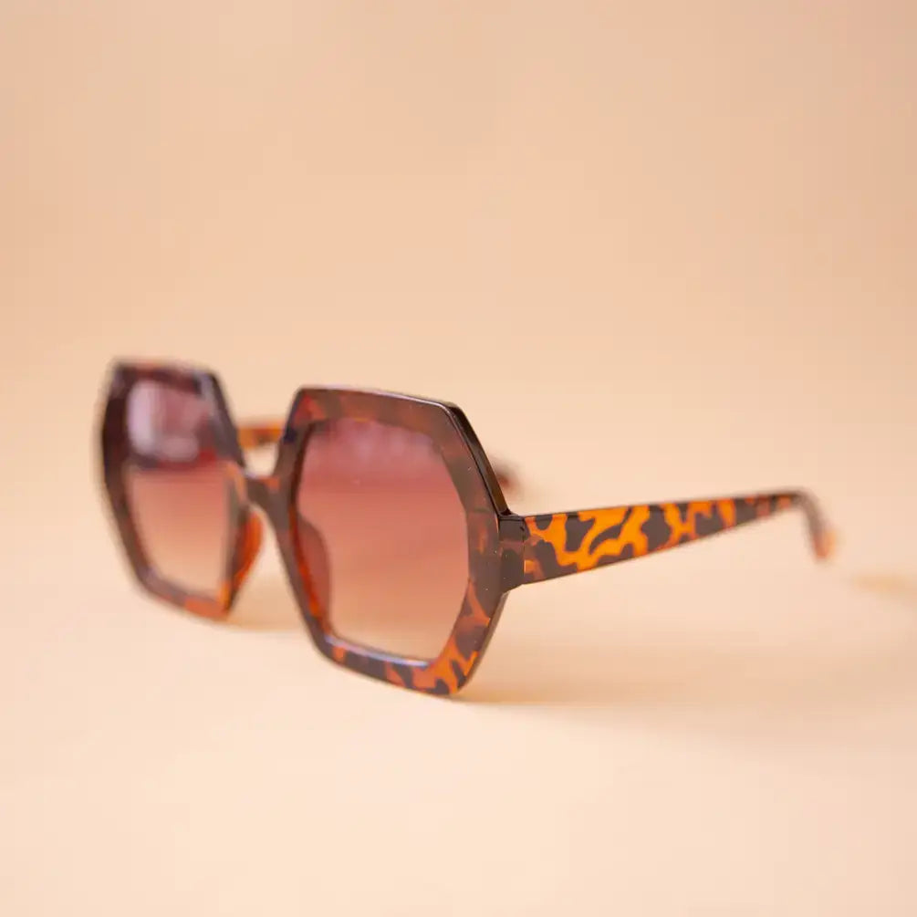 Sunglasses with leopard print frame and brown lenses on a beige background