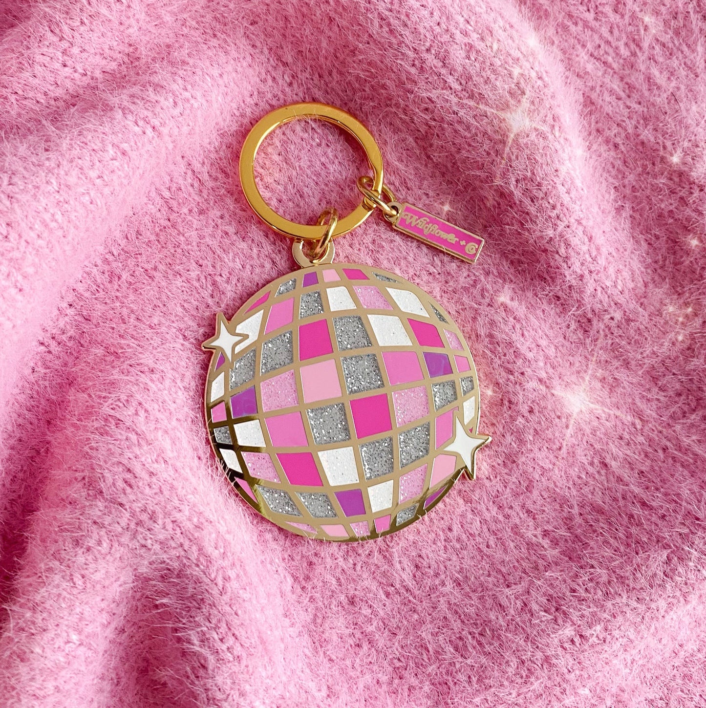 Pink and silver disco ball keychain on a pink textured background