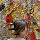 Person with a sushi hair clip in front of a colorful, textured wall.