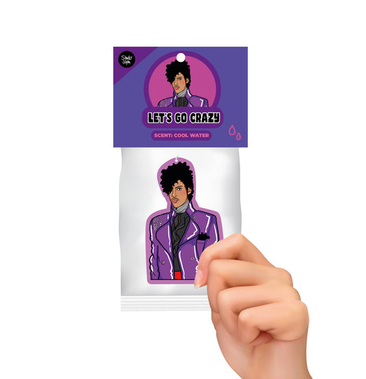 Hand holding a scented product packaging with a Prince in a purple jacket design and 'Let's Go Crazy' text.