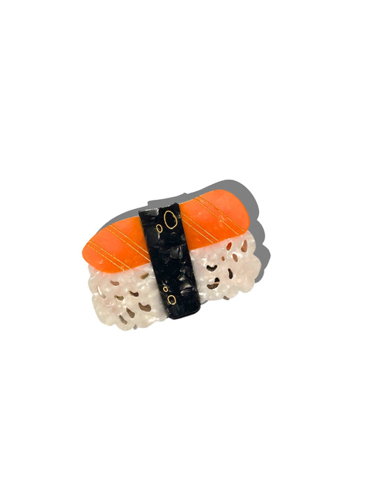 Sushi-shaped hair clip with orange fish and white rice on a white background