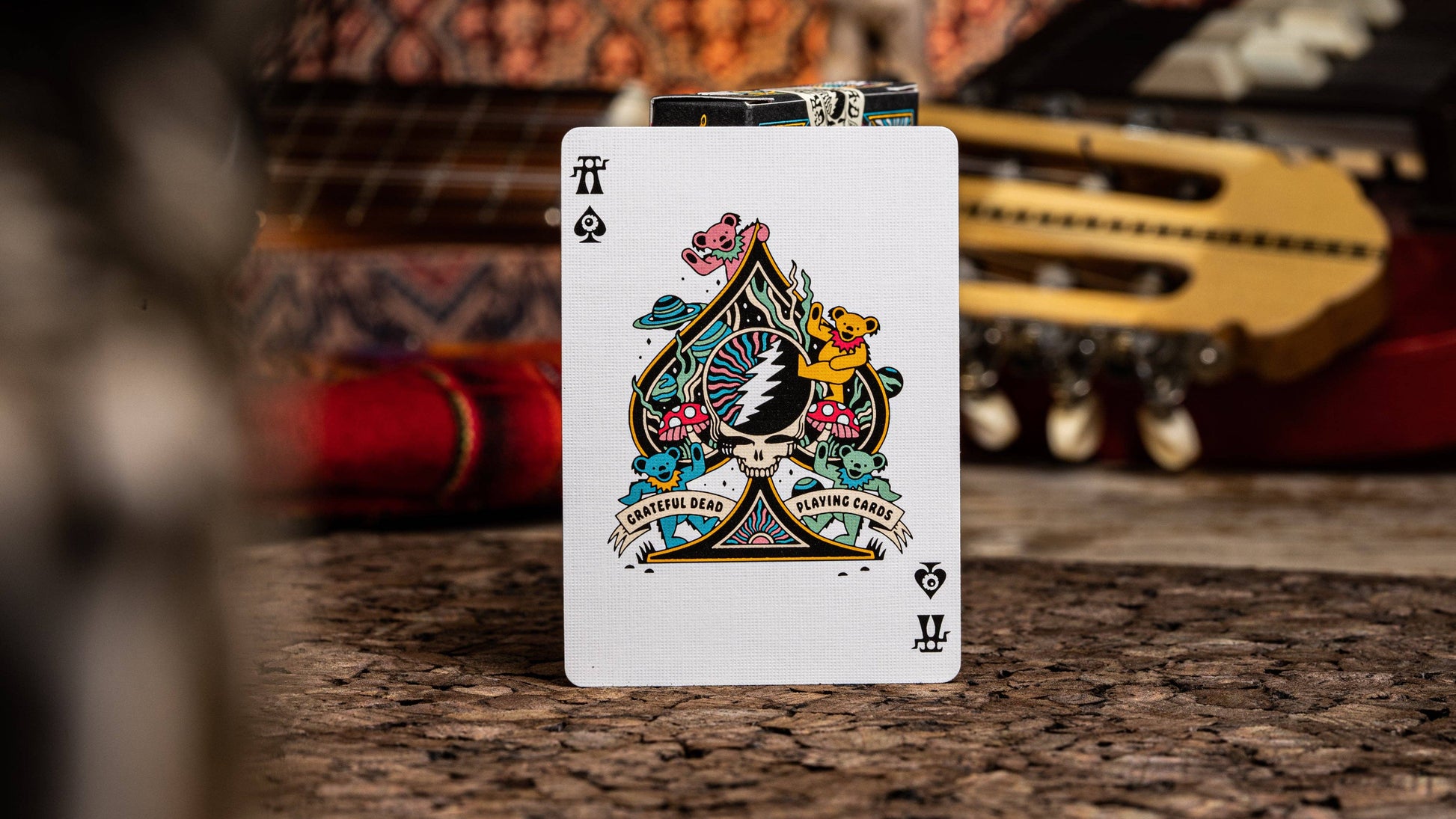 Playing card with floral design on a wooden surface with blurred guitar in the background