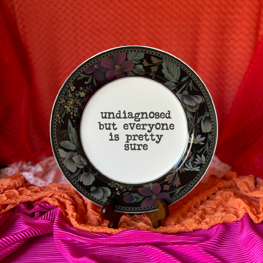 Decorative plate with floral design and text on a colorful fabric background
