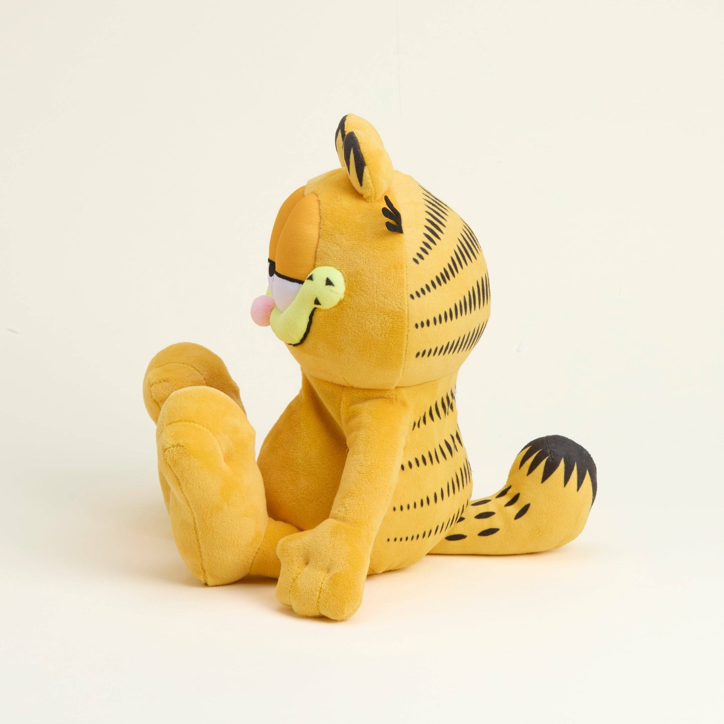 Yellow cat Garfield plush toy with black stripes on a beige background