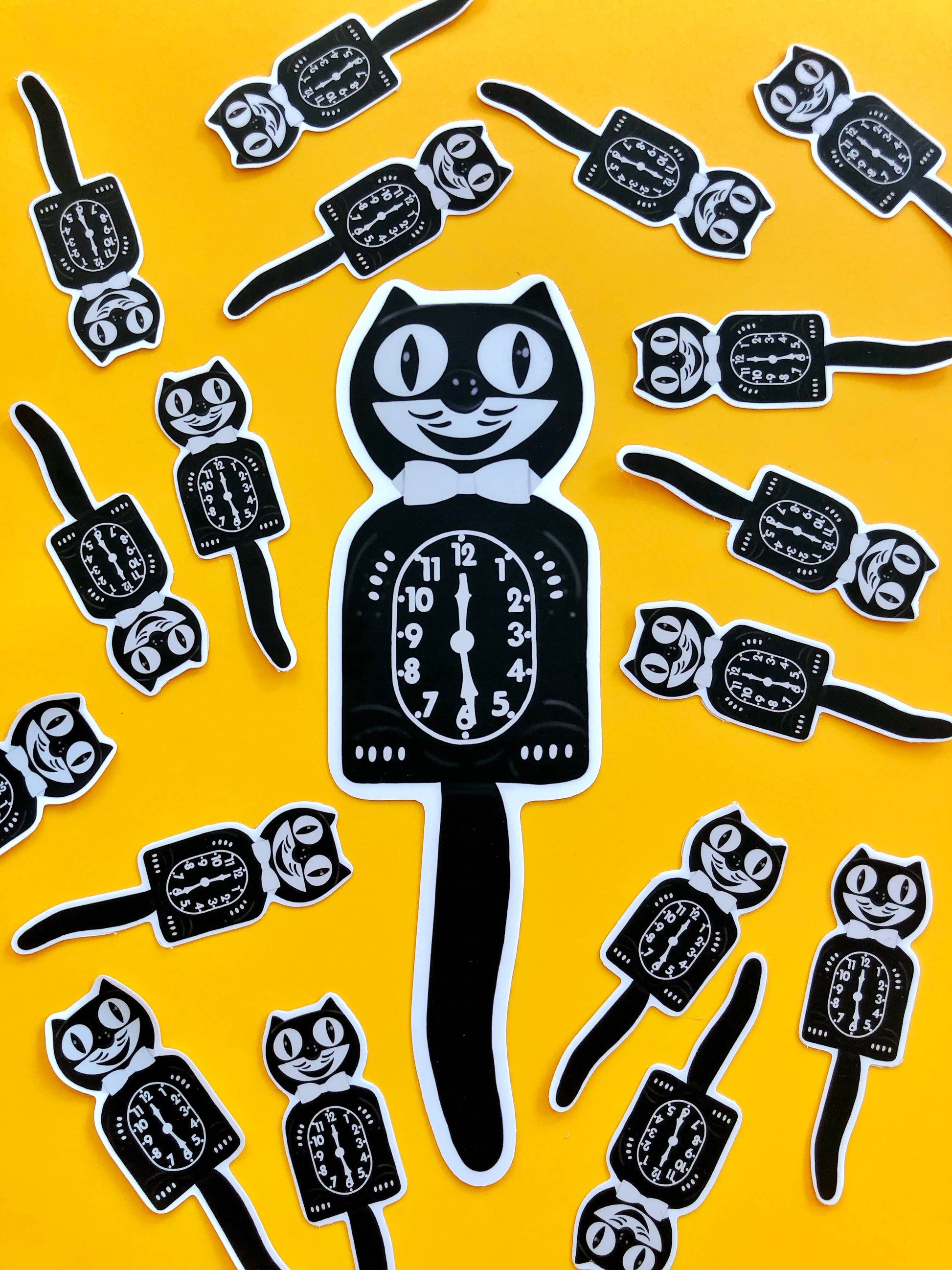 Black cat-shaped clocks with a clock face on a yellow background