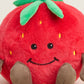 Plush strawberry toy with a smiling face on a white background