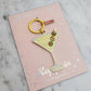 Keychain shaped like a martini glass with olives on a pink card with 'Wildflower Co' branding.