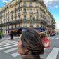 Person with a bun wearing a decorative cake hair clip in an urban street setting