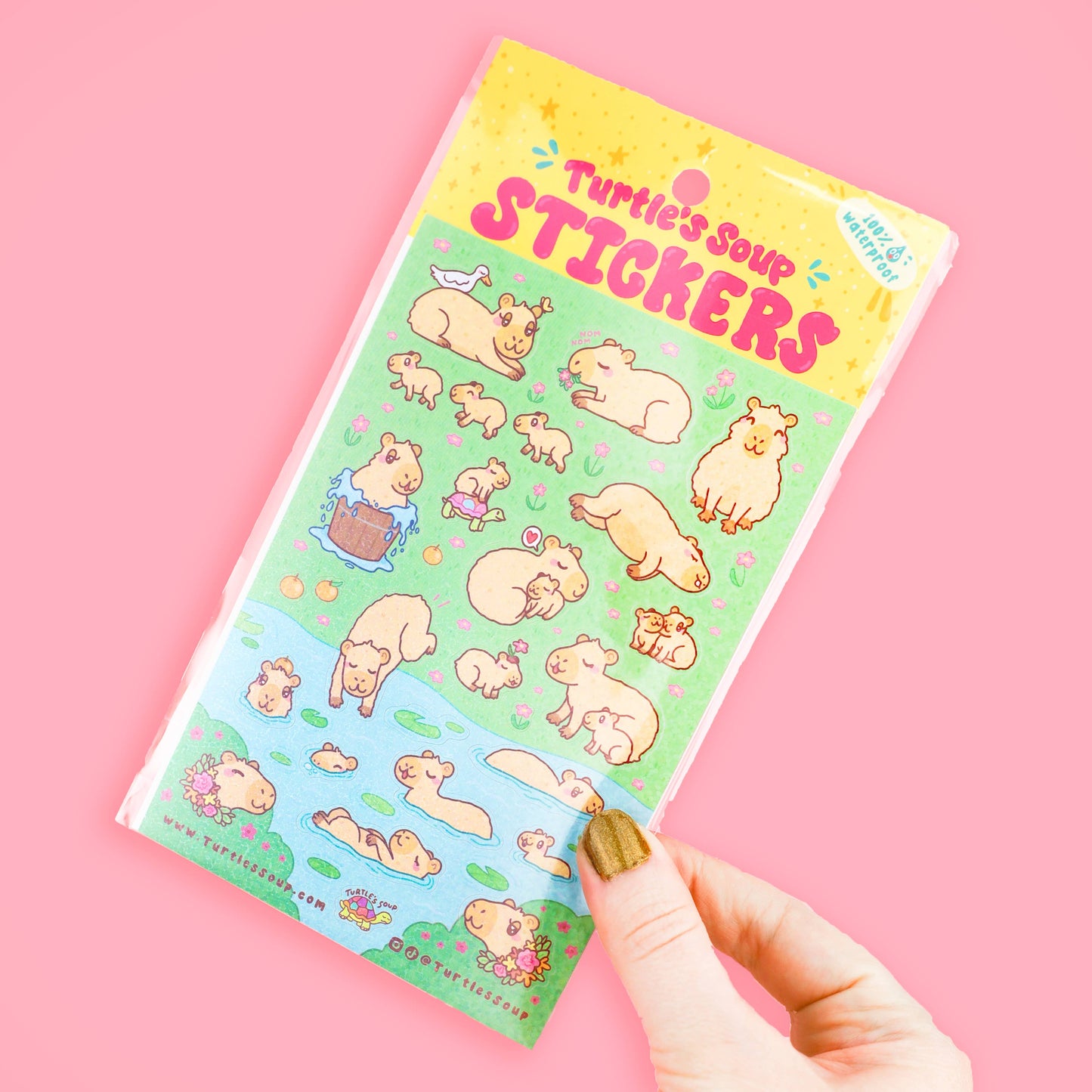 Sheet of cartoon animal stickers held by a hand on a pink background