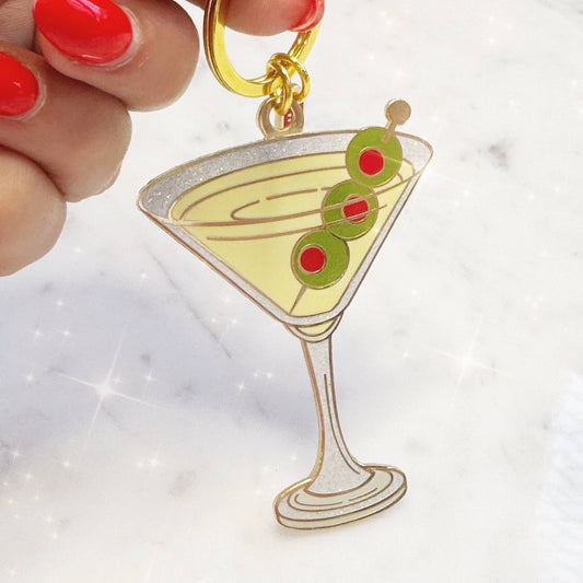 Martini glass keychain with olives held by a hand on a white background