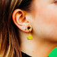Close-up of an ear wearing a yellow frog-shaped earring.