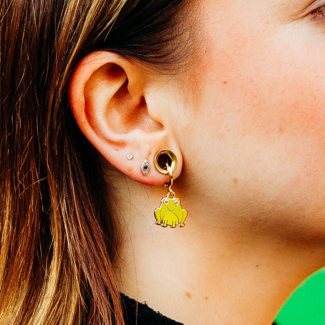 Close-up of an ear wearing a yellow frog-shaped earring.