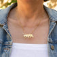 Gold necklace with a tiger pendant worn by a person in a denim jacket.