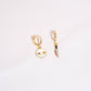 Gold skull-shaped earring with a bloody knife earrings design on a white background