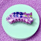 Purple and blue cat-shaped comb on a light green circular base with a purple textured background