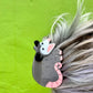 Hair clip shaped like a possum with pink accents on a person's hair against a green background