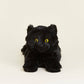 Black plush cat with yellow eyes on a beige background