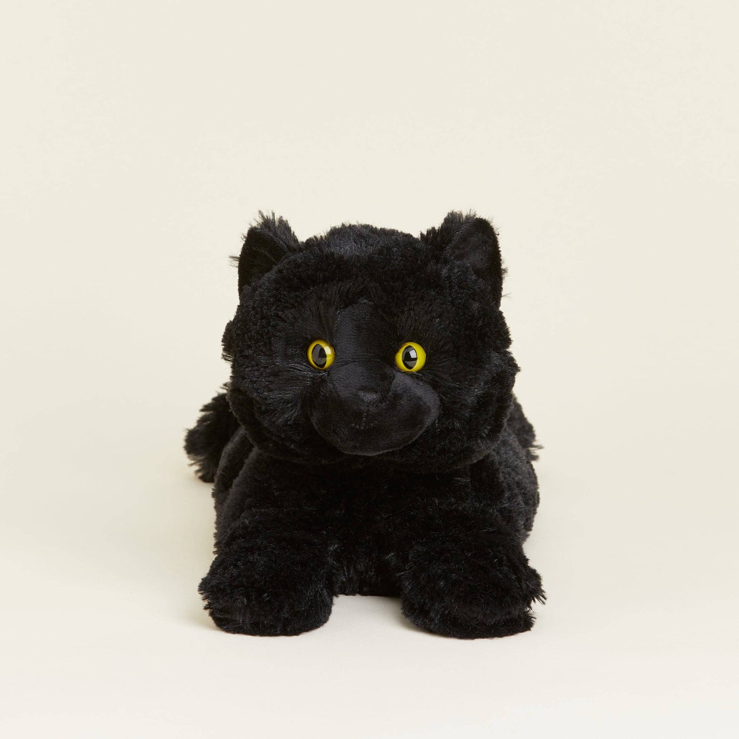 Black plush cat with yellow eyes on a beige background