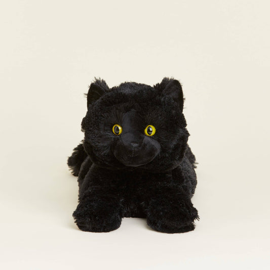 Black plush cat with yellow eyes on a beige background