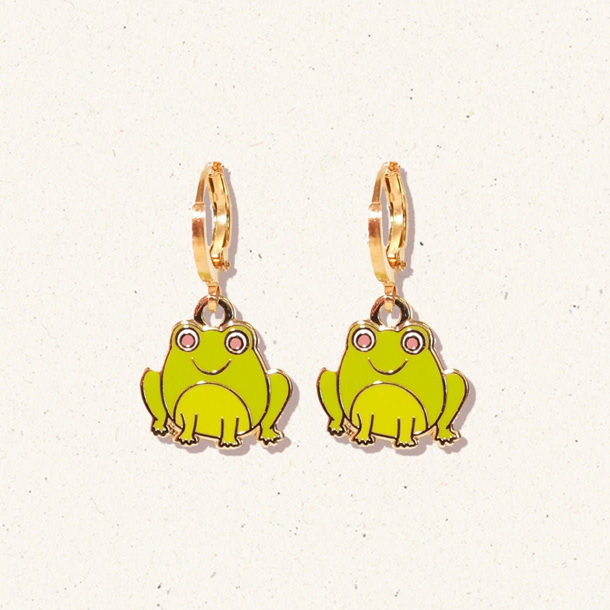 Frog-shaped earrings with gold hooks on a light background