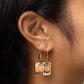 Close-up of an ear wearing a pair of colorful earrings with a dark background