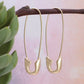 Gold paperclip earrings hanging on a branch with a soft background