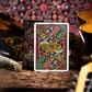 Colorful playing card box with intricate design on a wooden surface with musical instruments in the background.