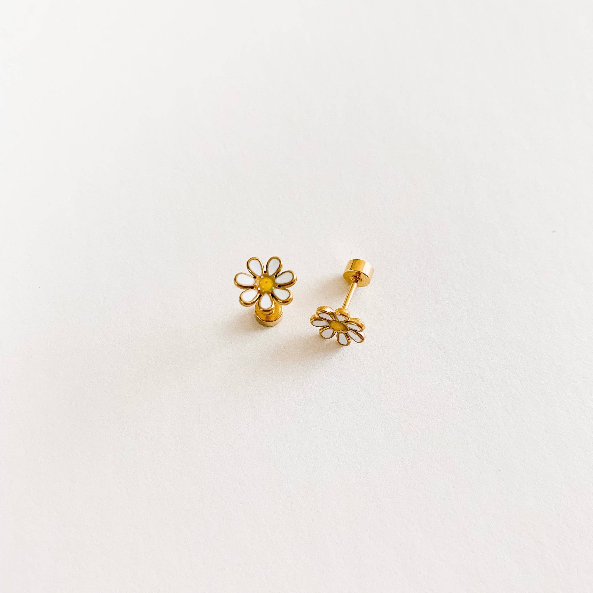 Gold flower-shaped earrings on a light gray background