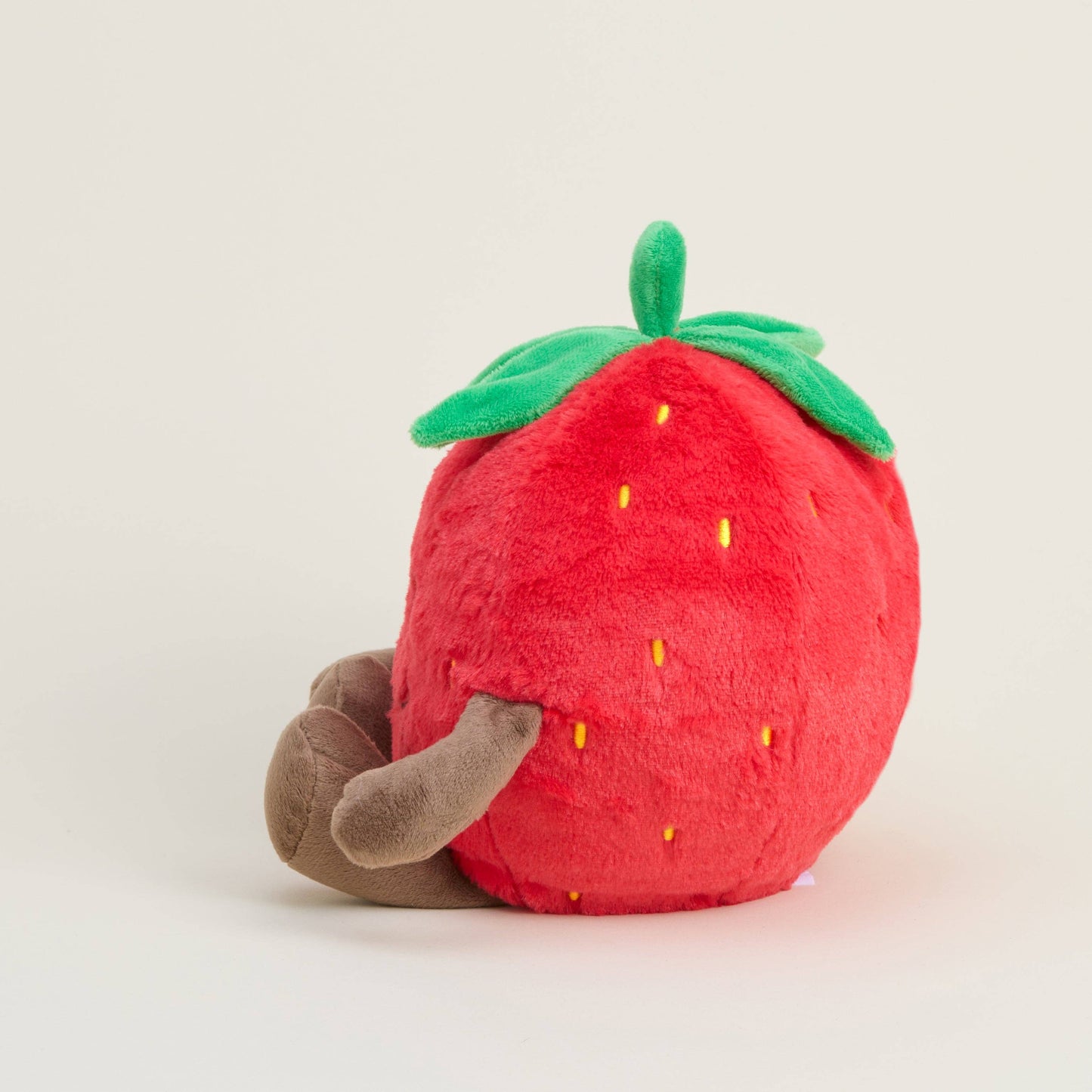 Plush strawberry toy with a brown stem on a light gray background