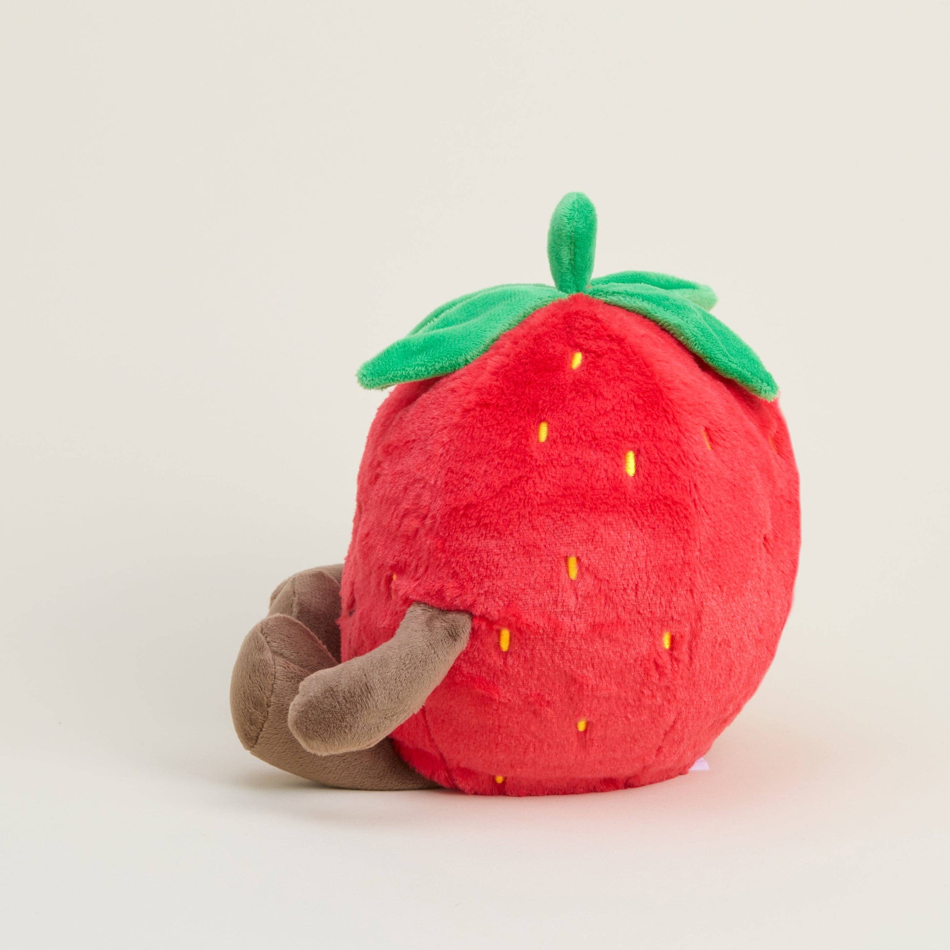 Plush strawberry toy with a brown stem on a light gray background