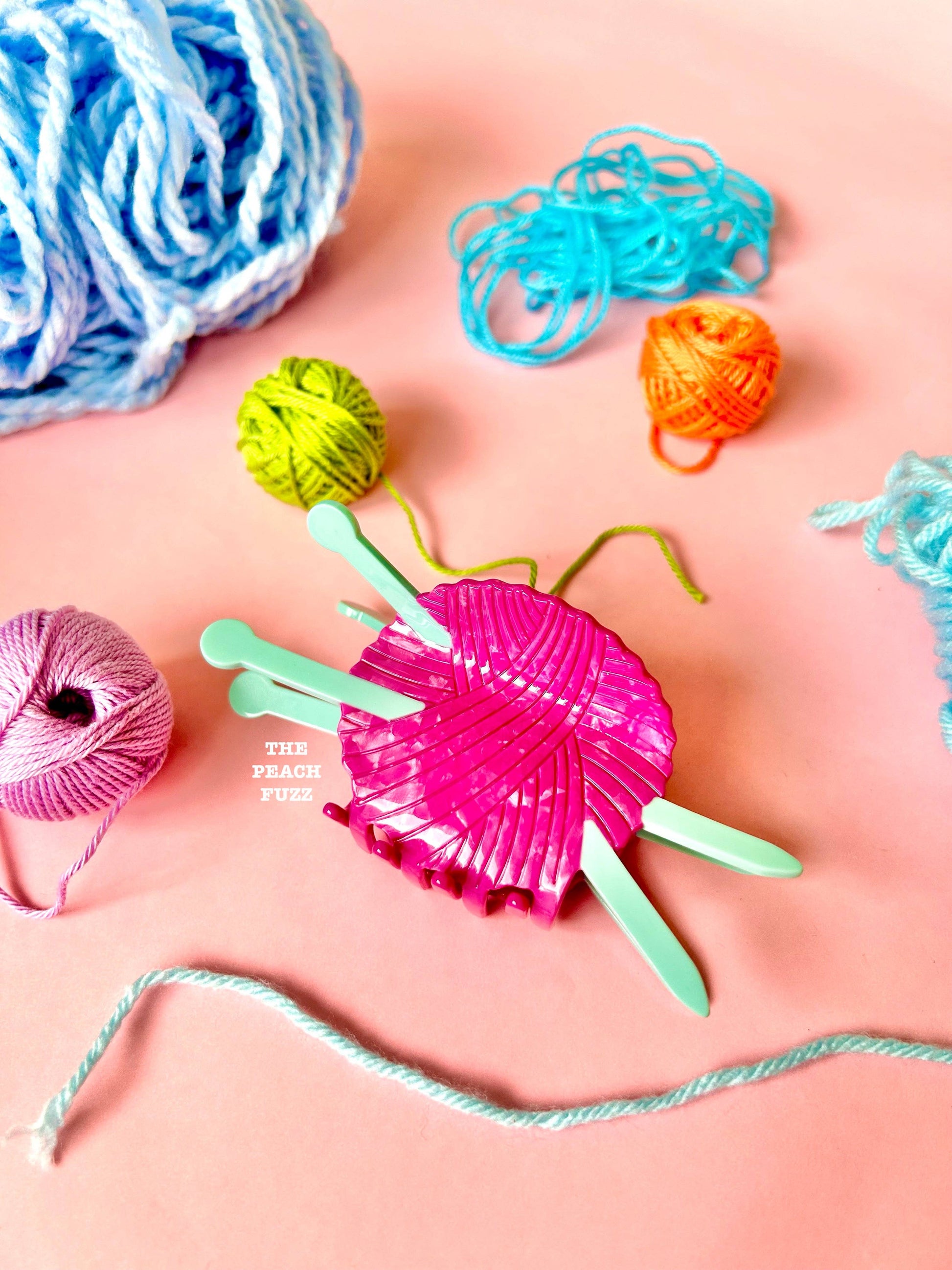 Colorful yarn and knitting tools hair claw clip on a pink background