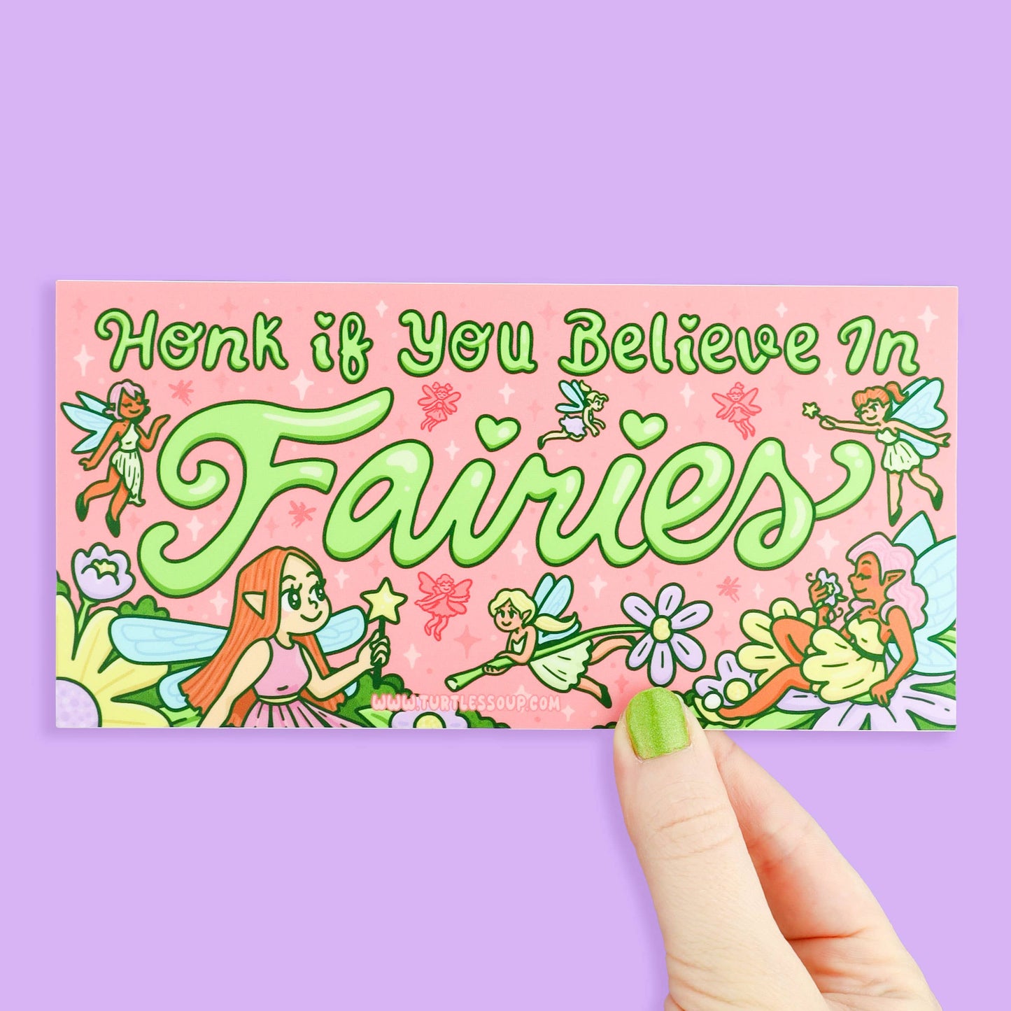 Sticker with fairies and text 'Honk if you believe in fairies' held by a hand on a pink background