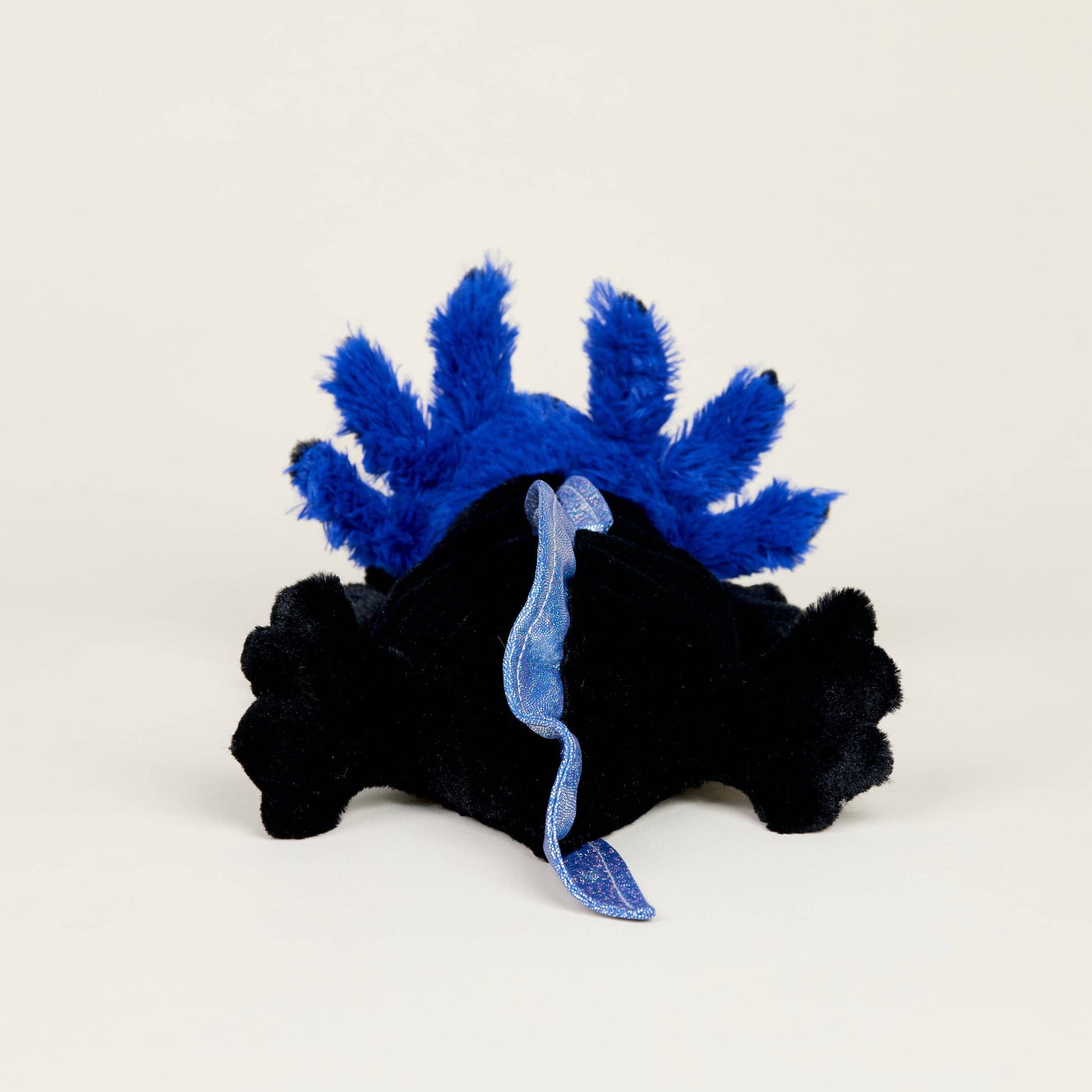 Black plush toy with blue details on a white background