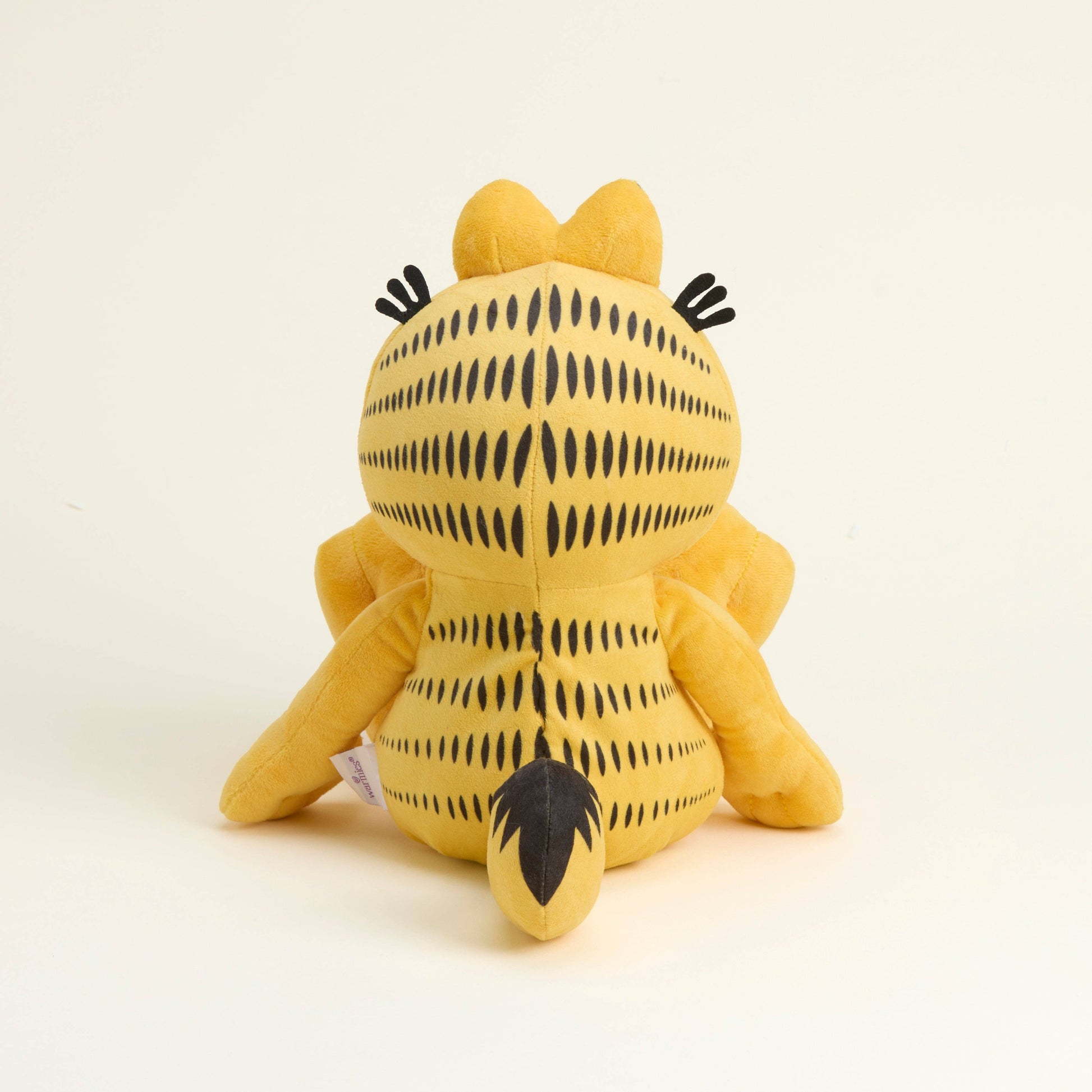 Yellow cat Garfield plush toy with black patterns on a beige background