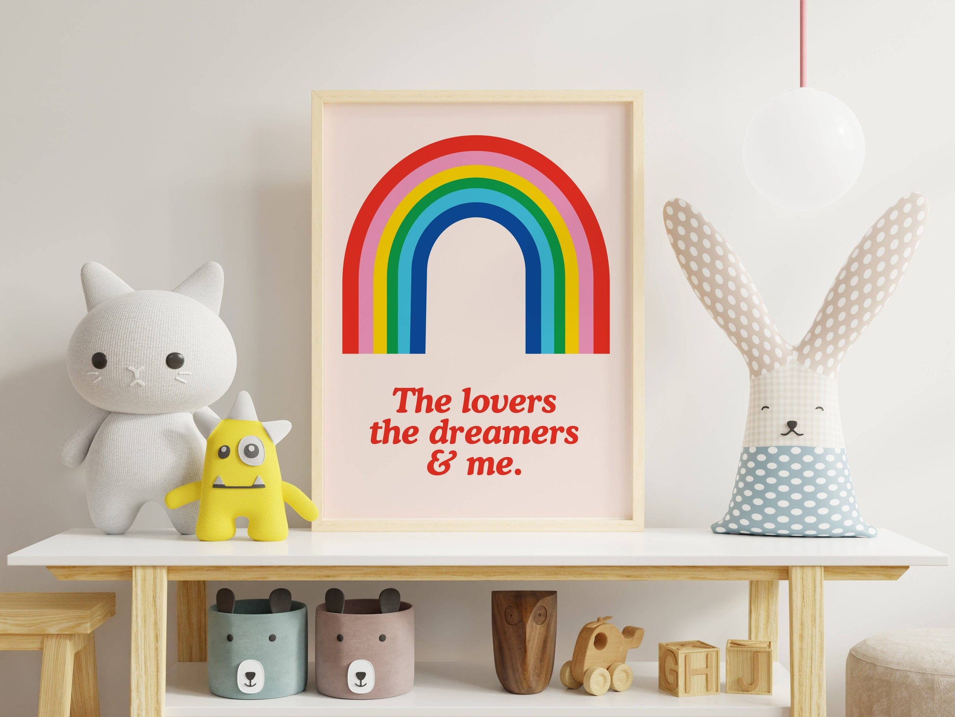 Framed rainbow poster with text on a shelf with toys and decor