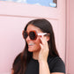 Woman wearing sunglasses in front of a pink vehicle