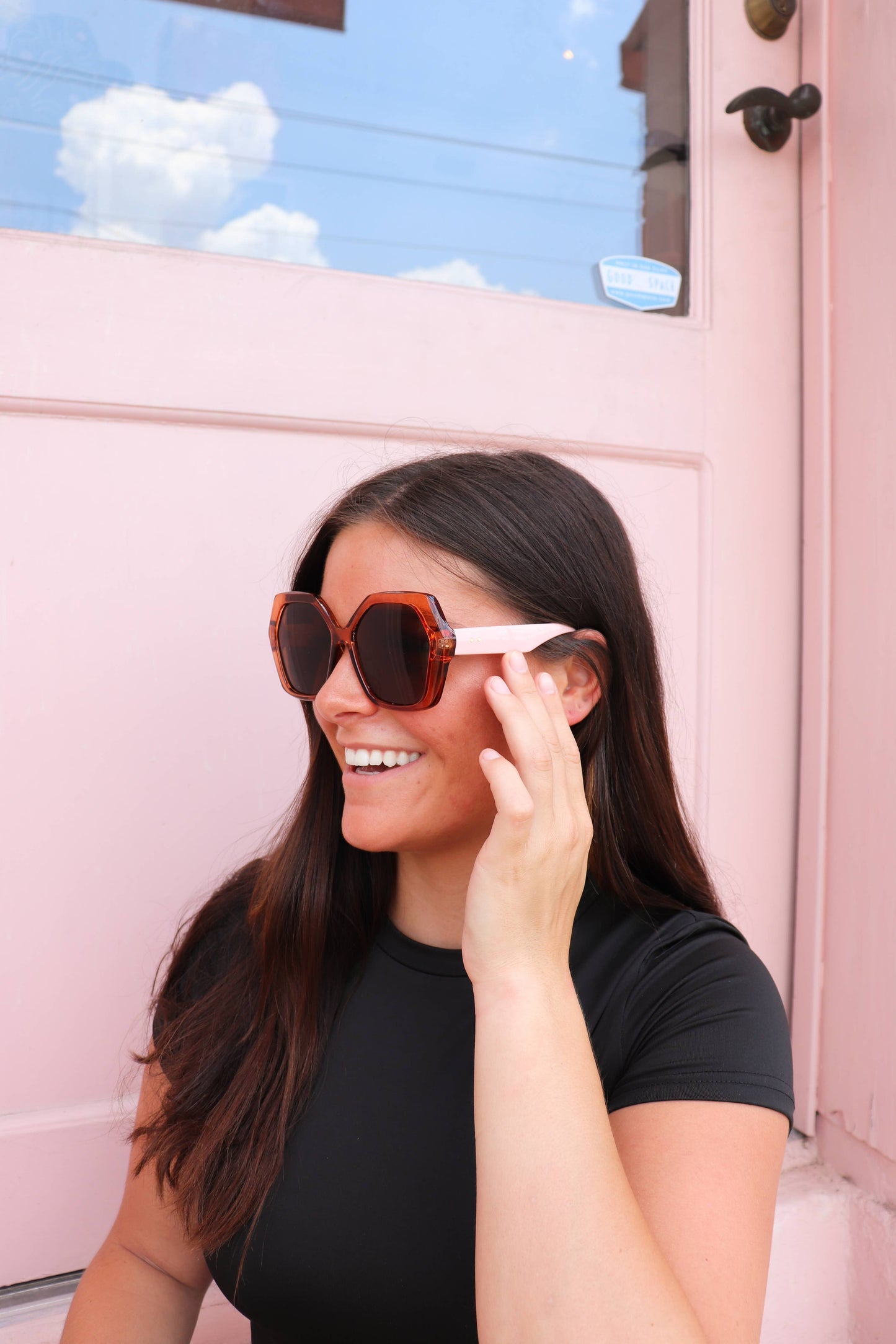 Woman wearing sunglasses in front of a pink vehicle