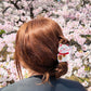 Person with a lucky cat hair claw design against a cherry blossom background