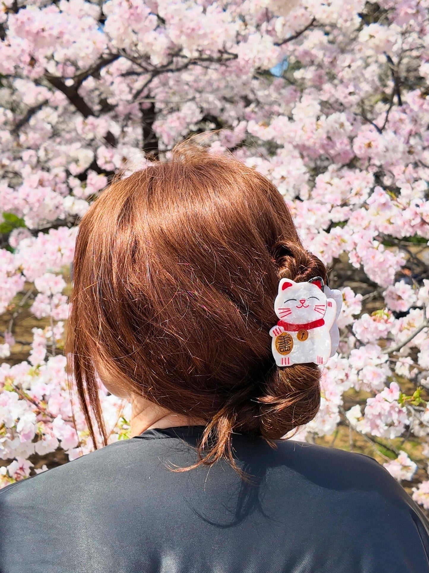Person with a lucky cat hair claw design against a cherry blossom background