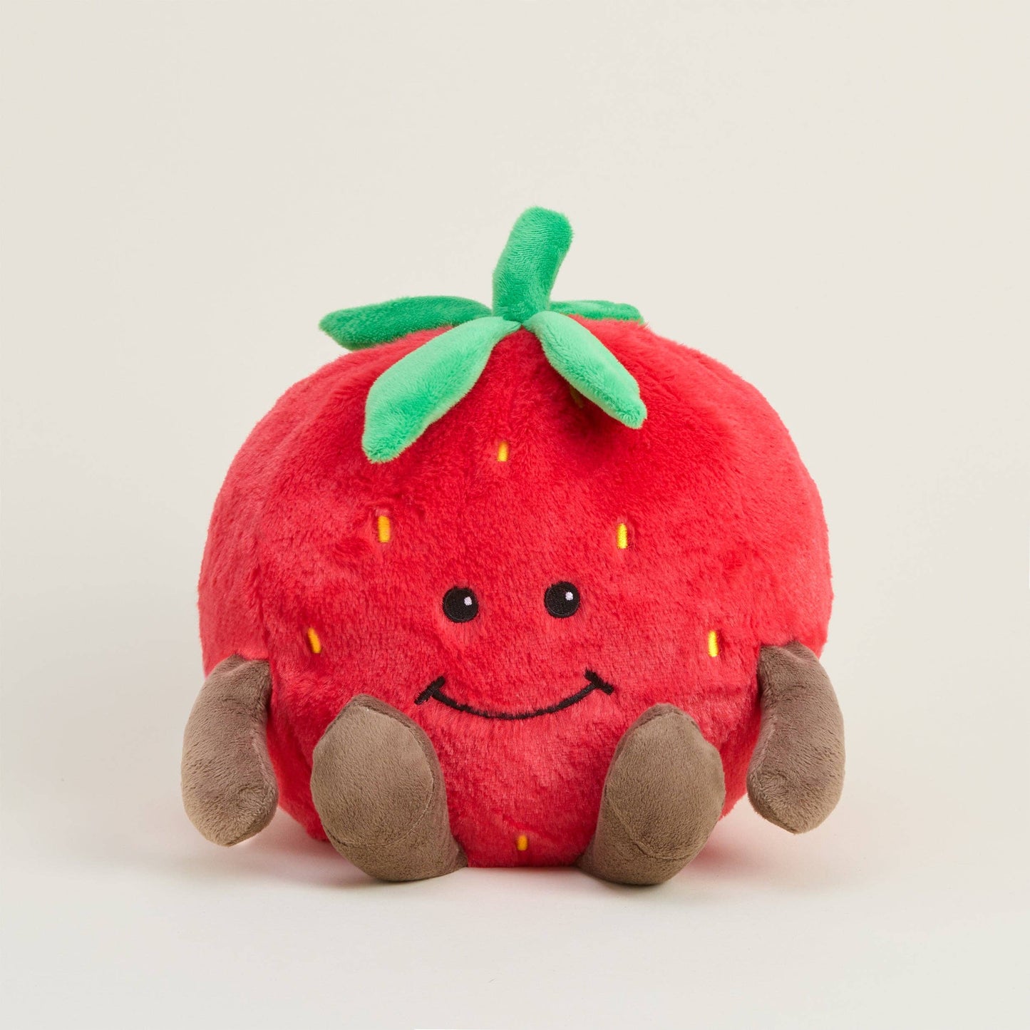 Plush toy strawberry with a smiling face on a light background