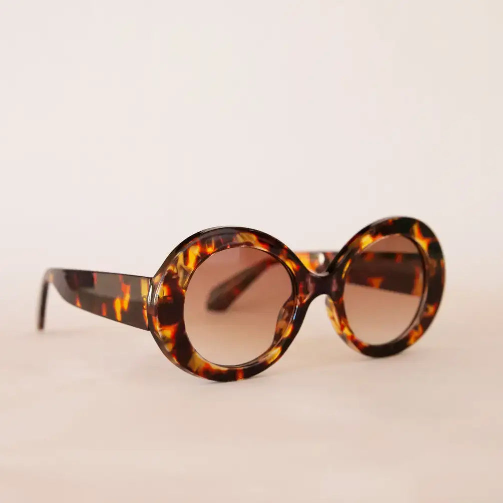 Round tortoiseshell sunglasses on a beige background