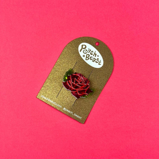 Red rose hair clip on a gold card with 'Peach Beast' branding against a pink background