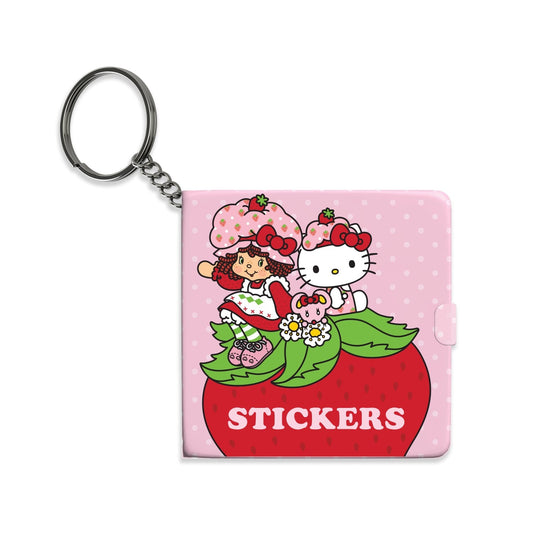 Keychain with strawberry shortcake and hello kitty sticker book on a pink background
