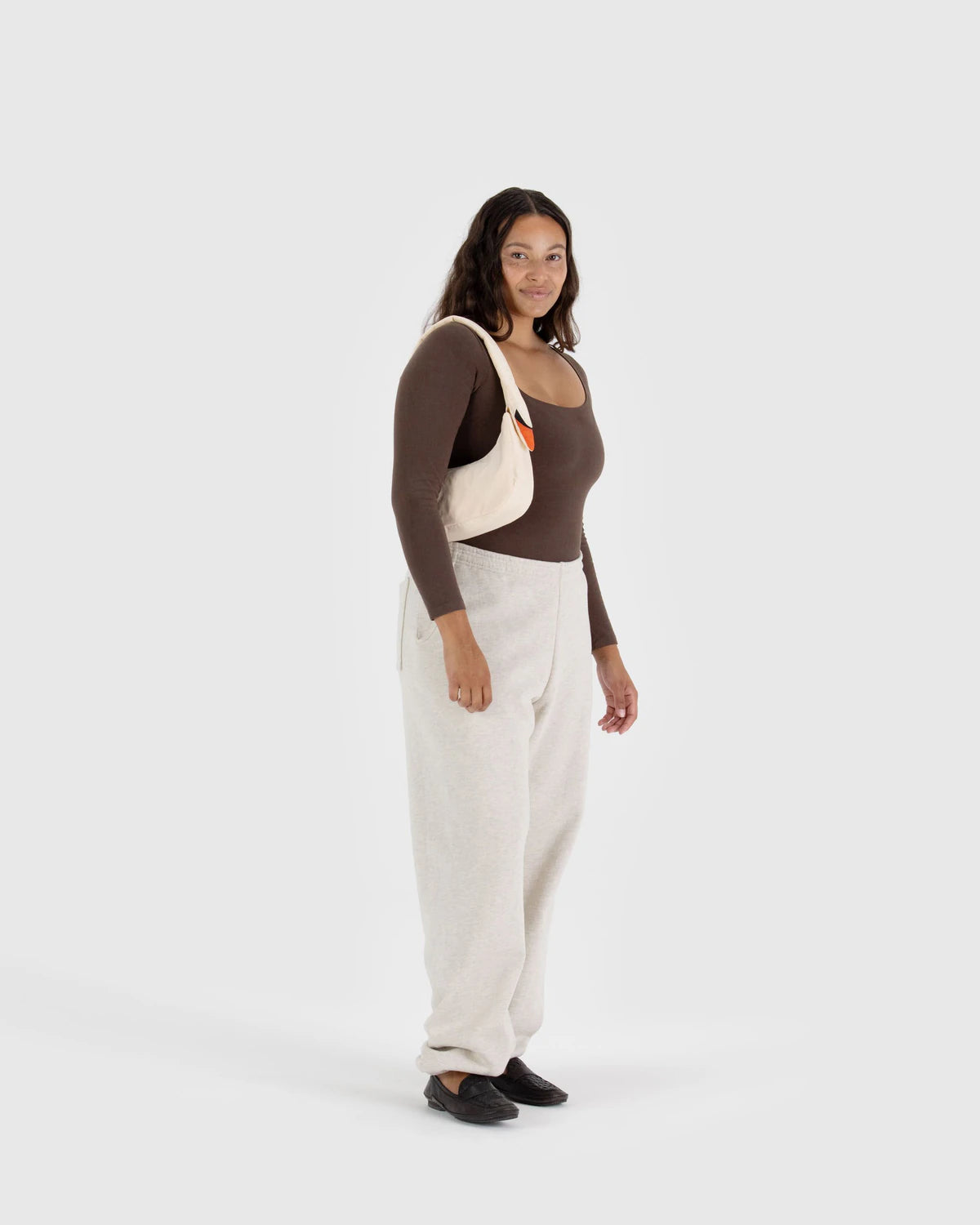 Woman wearing a brown top, beige apron, and white pants on a white background