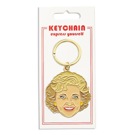 Gold keychain with a face design on a white card with red text.