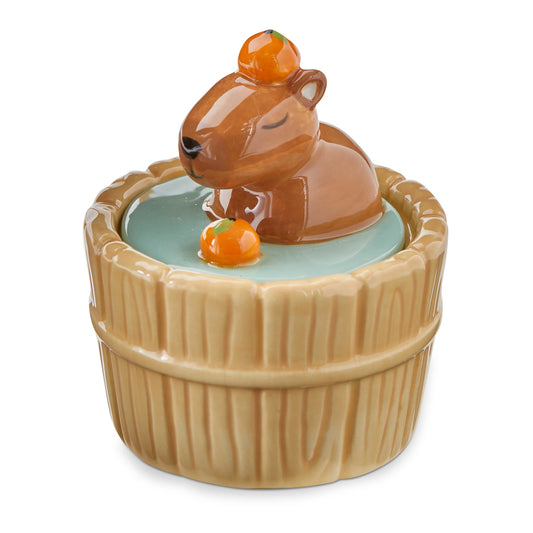 Ceramic container with a capybara design on top, sitting inside a wooden barrel. taking a bath with oranges