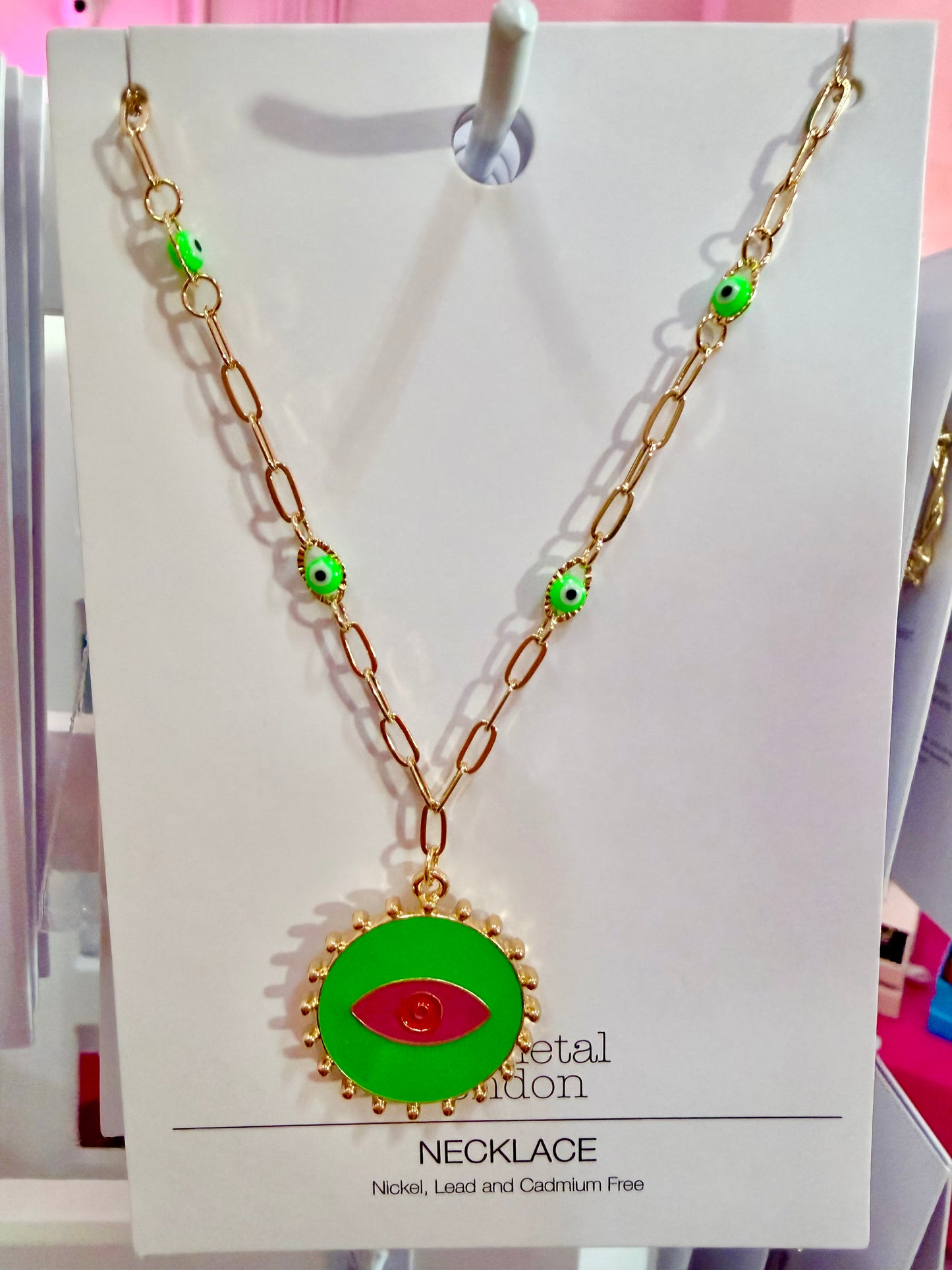 Necklace with green pendant with a red eye in the center on a display card