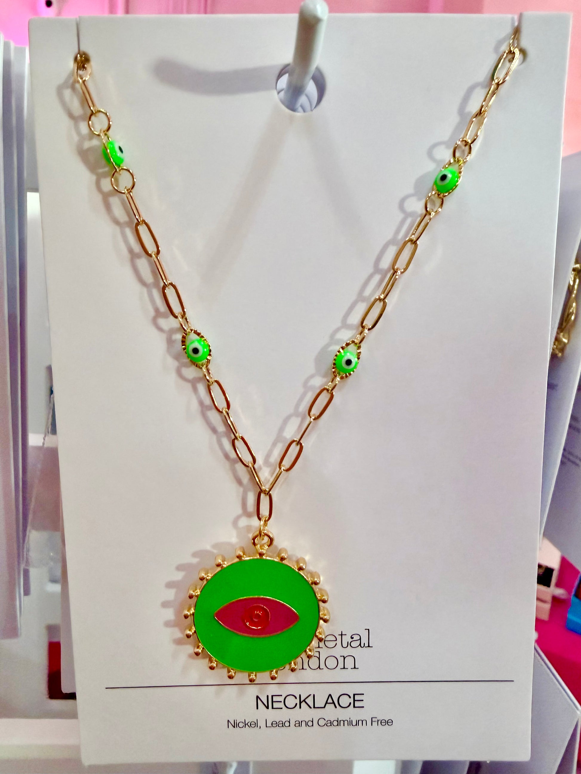 Necklace with green pendant with a red eye in the center on a display card